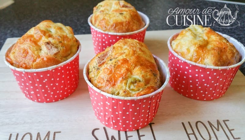 Muffins salés dorés au fromage et mortadelle, cuits dans des caissettes rouges à pois blancs, posés sur une planche en bois gravée
